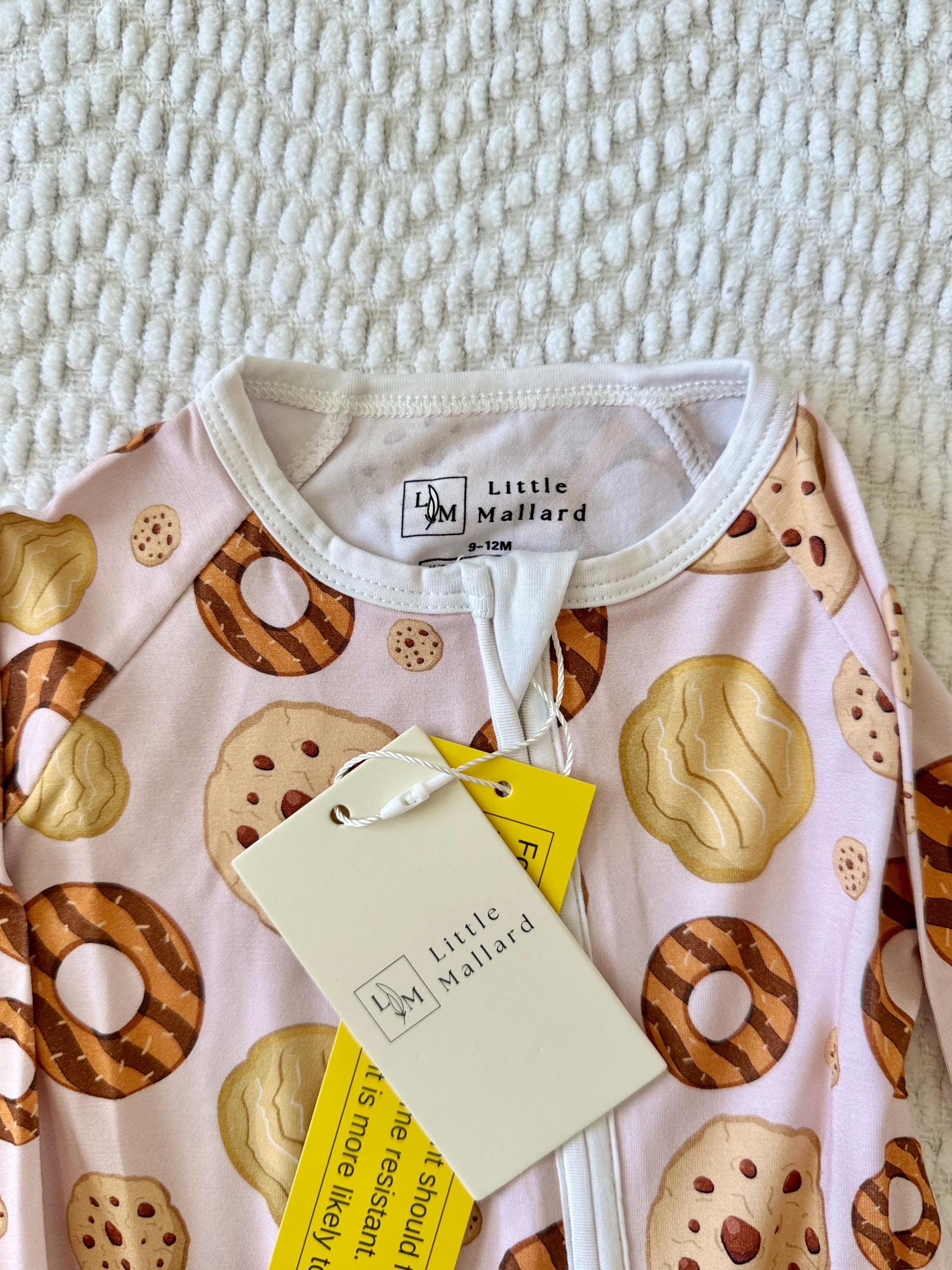 Bamboo Baby onesie with cookie pattern and 'Little Mallard' brand tag on a textured surface with stretchy fabric