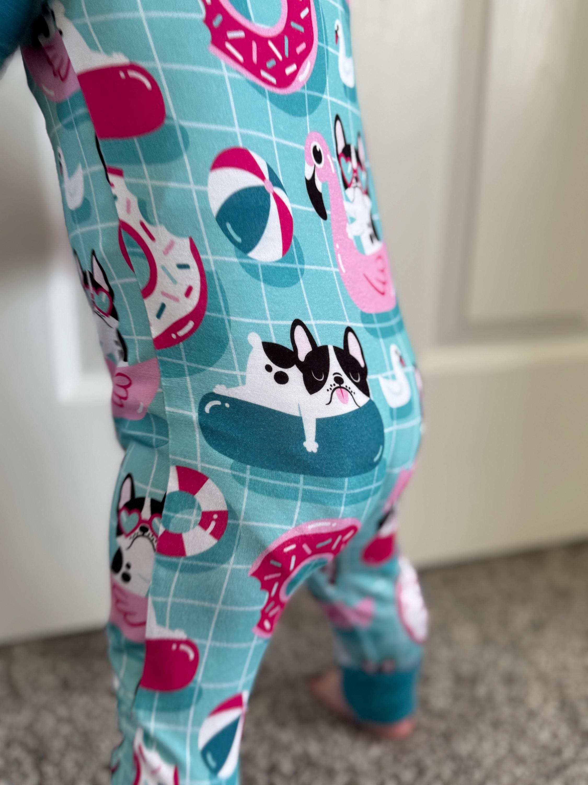 Baby wearing stretchy and soft pajama with cartoon dog and beach ball pattern on a light blue background.