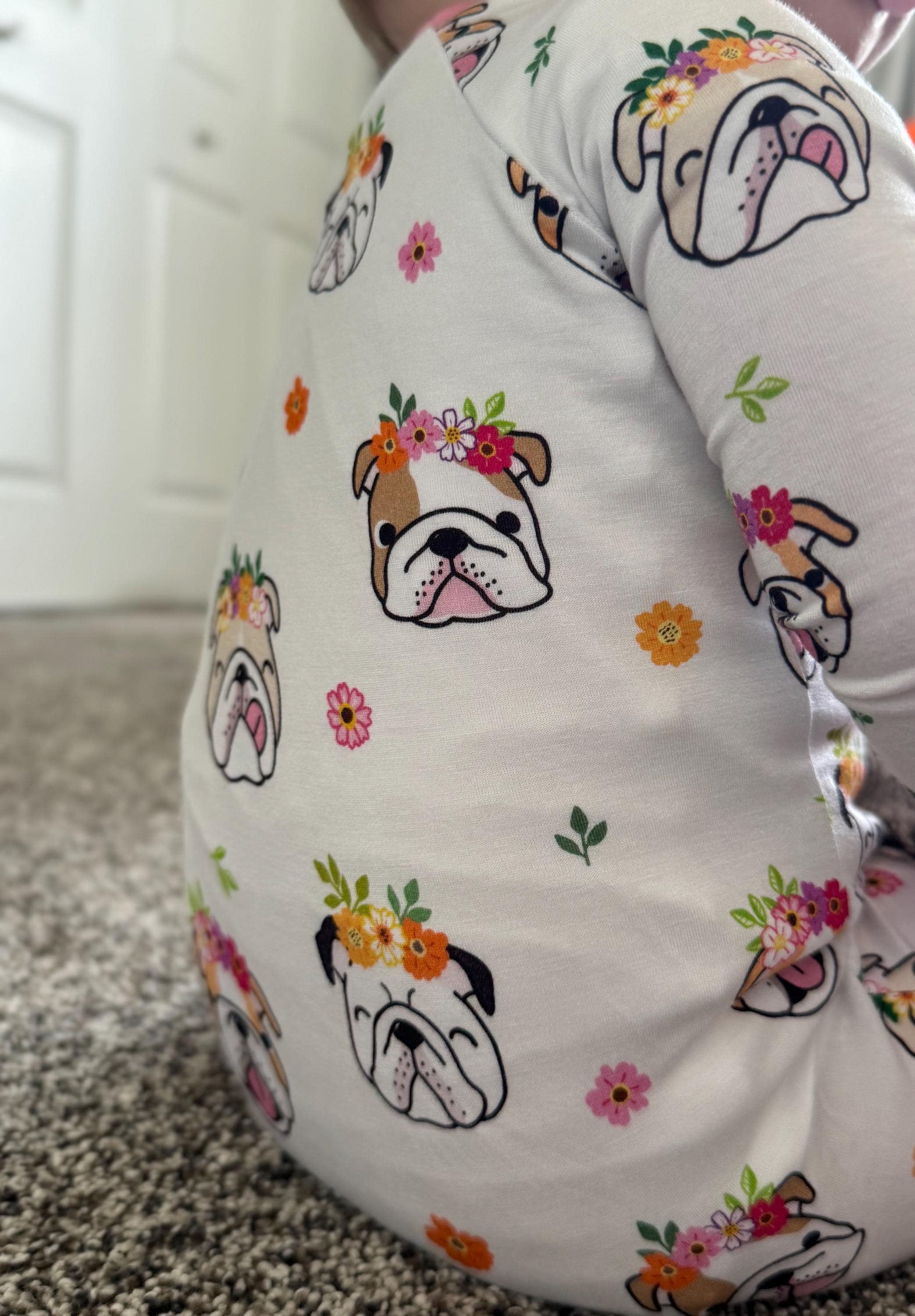 Baby wearing white bamboo footie pajamas with convertible mittens and feet with dog and floral accents