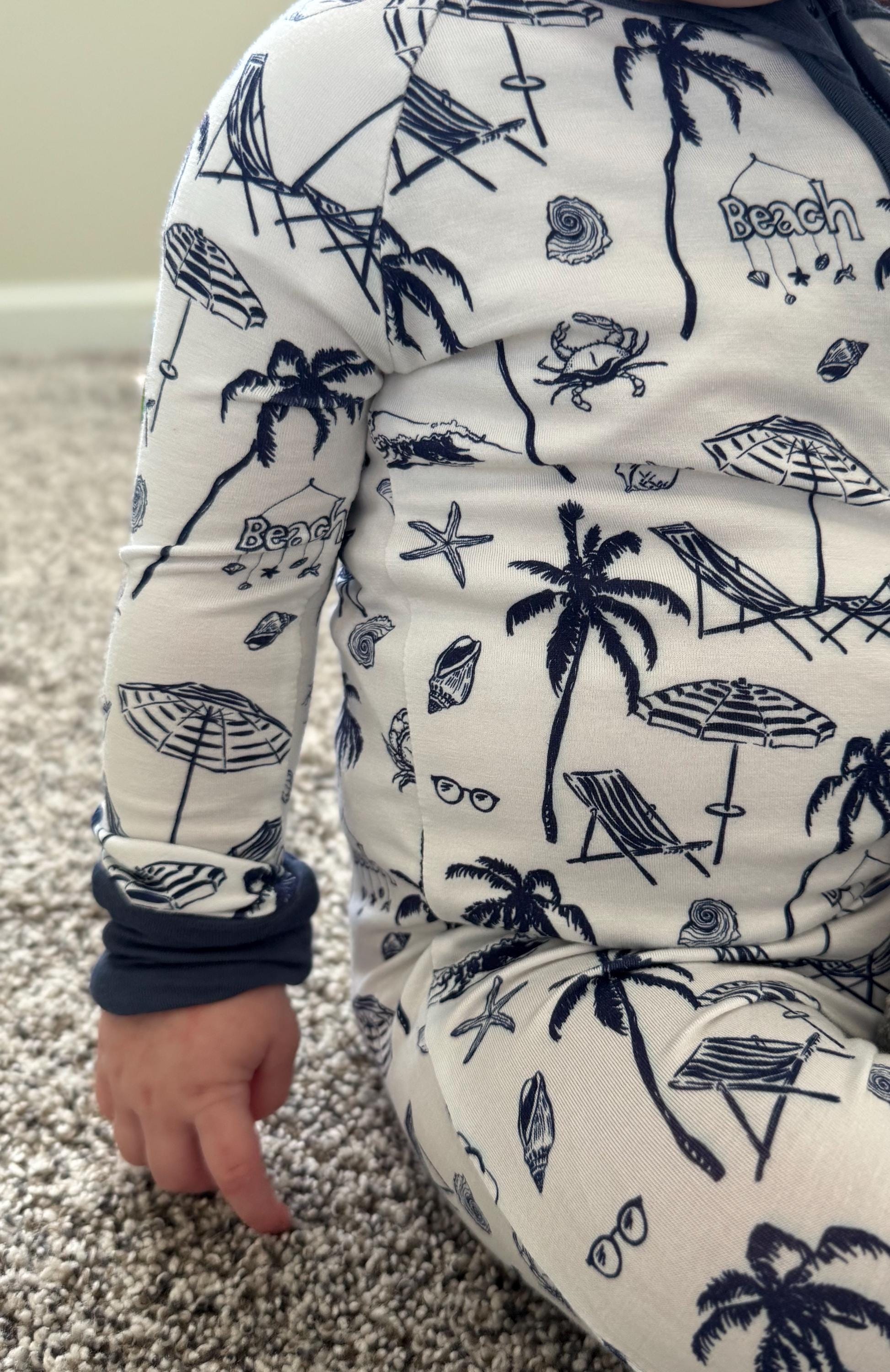 Super cute, super soft Children's pajamas with beach-themed design featuring palm trees, umbrellas, and lounge chairs on a white background.