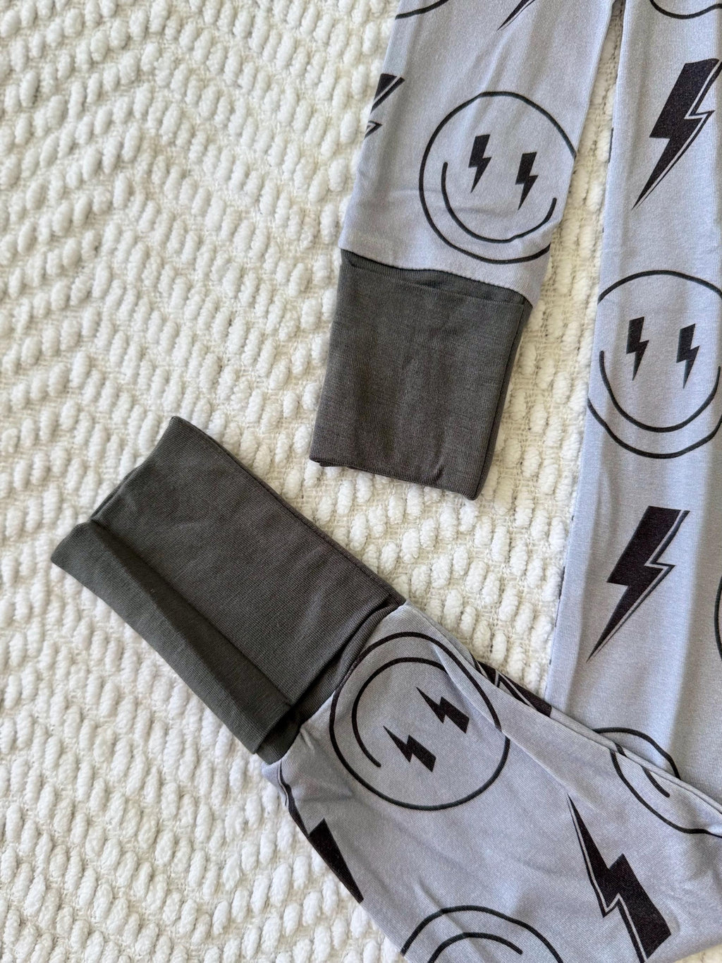 Super soft and breathable Gray baby pajama with black lightning bolt and smiley face patterns on a textured surface