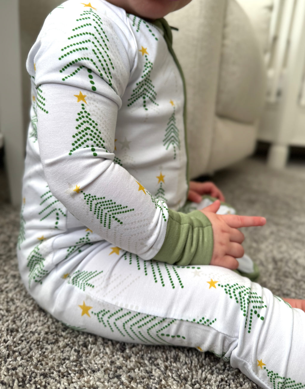 Infant wearing Christmas Bamboo Pajama white background with pine trees in light green and grey and stars. Bamboo pajamas are super soft, durable and adorable. The convertible footie pajamas have adjustable feet and mittens to grow with your little. 