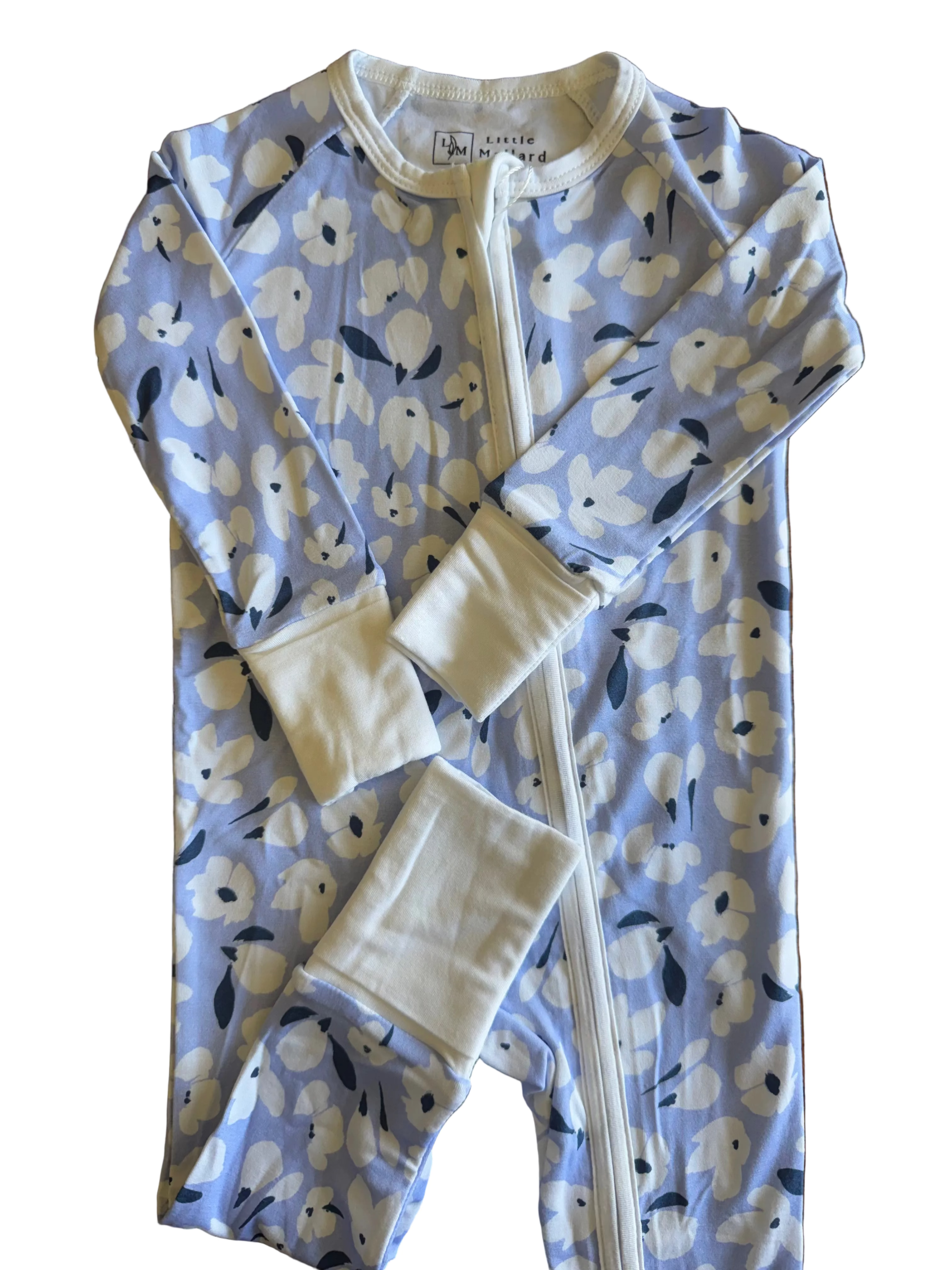 Folded periwinkle baby romper with whitefloral pattern on a whit surface. 