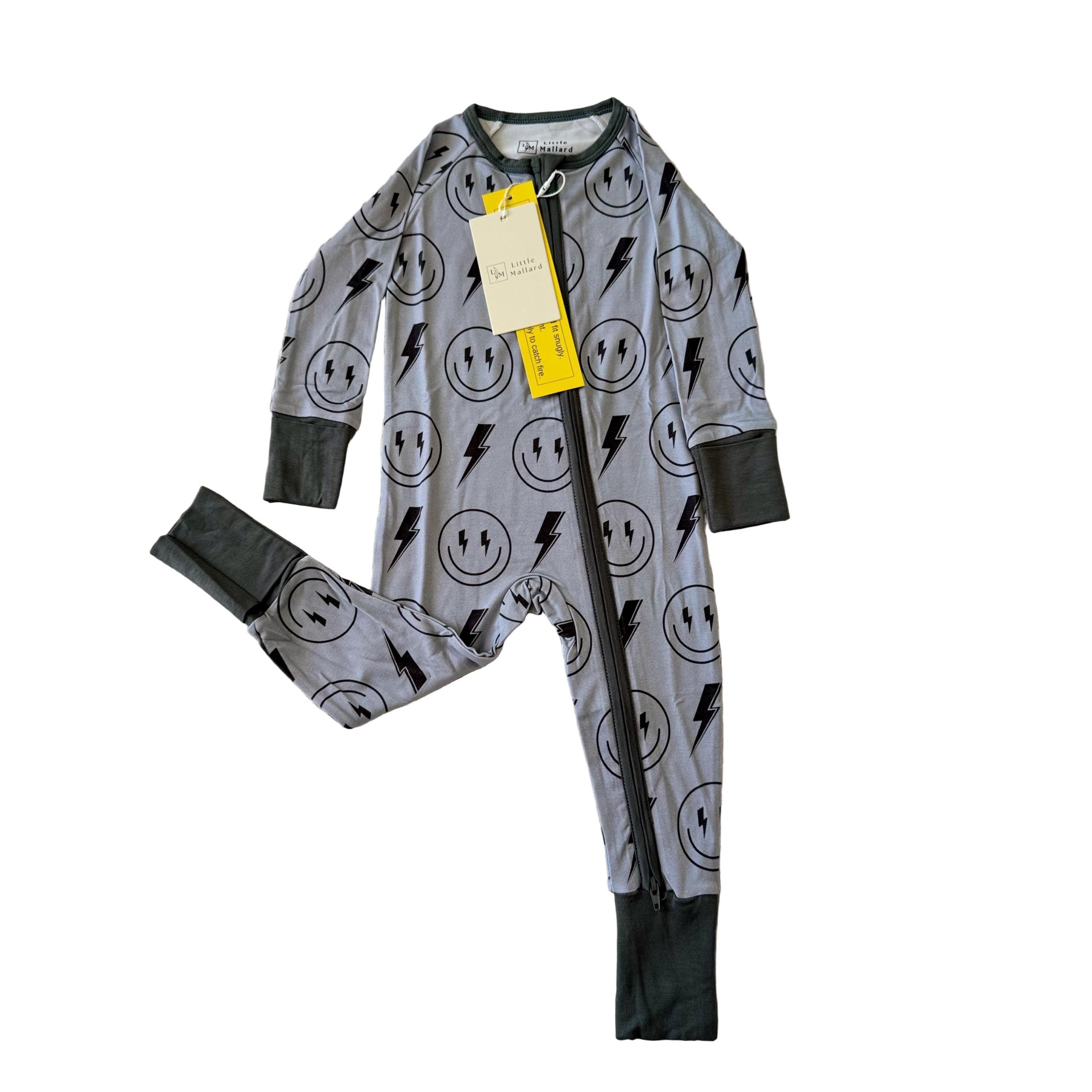Gray baby convertible bamboo pajama with black smiley face and lightning bolts pattern on a textured white surface