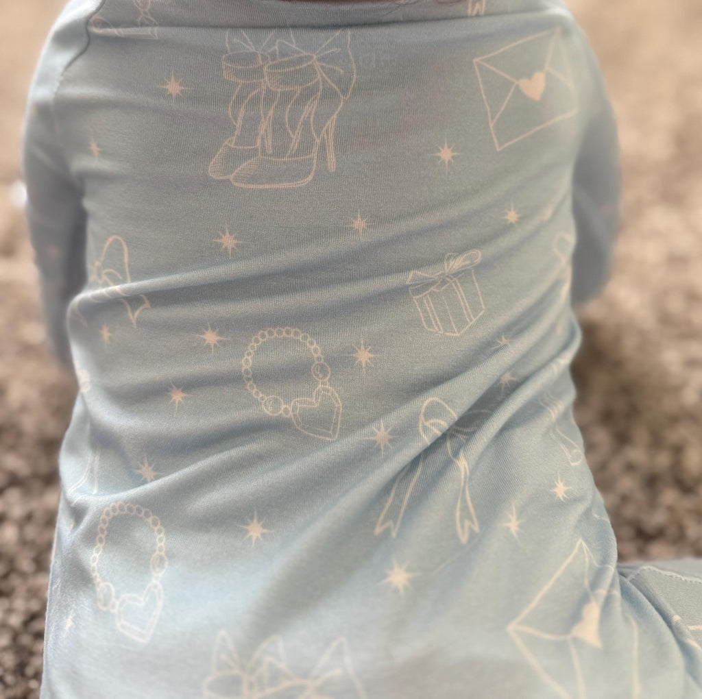 Baby wearing light blue bamboo pajamas with white girly designs on stretchy and soft fabric. 