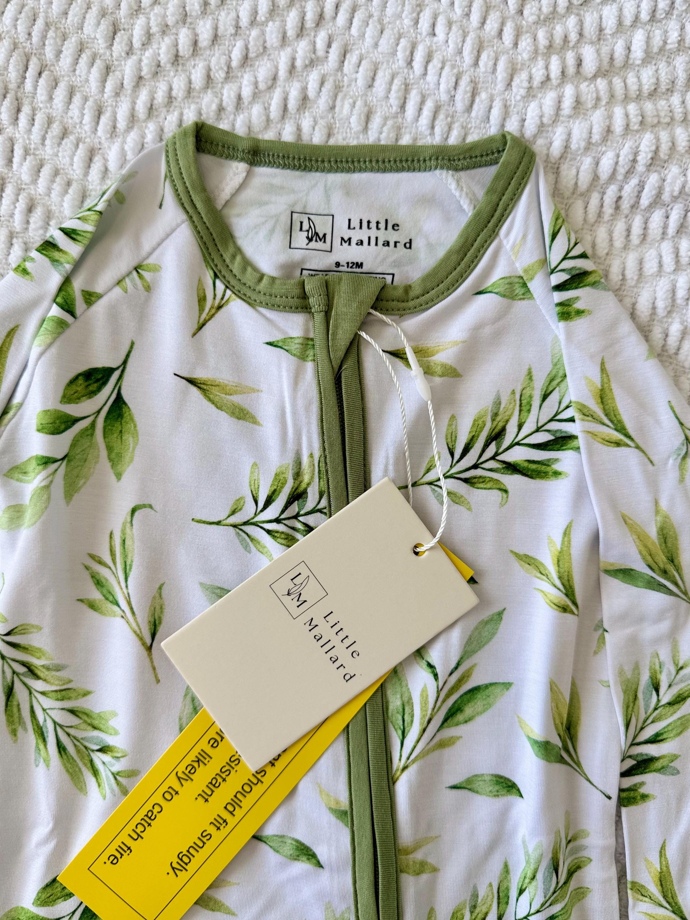 Soft bamboo Baby onesie with green leaf pattern and 'Little Mallard' tag on a textured surface
