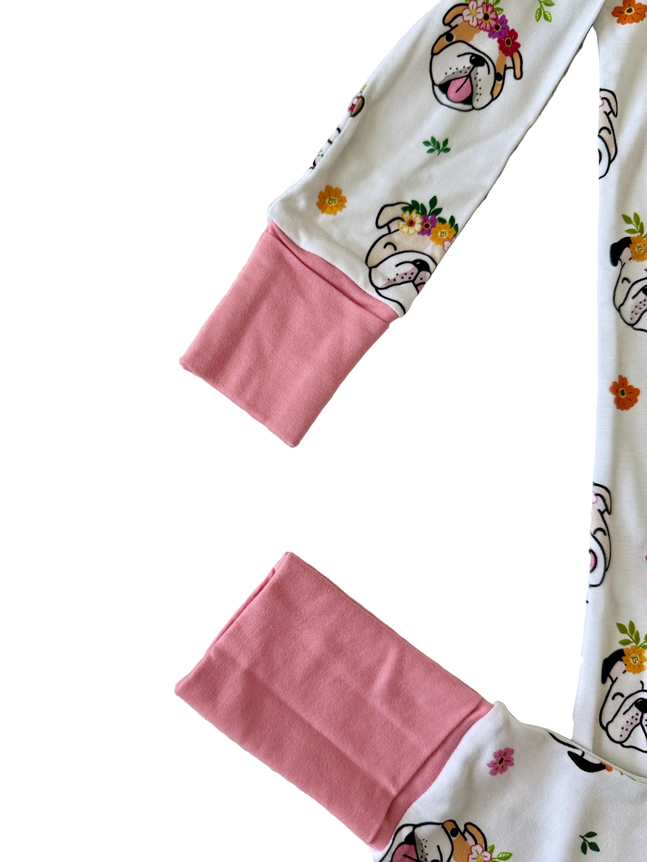 White baby sleeper with double zipper with dog print and flowers with pink accents. 