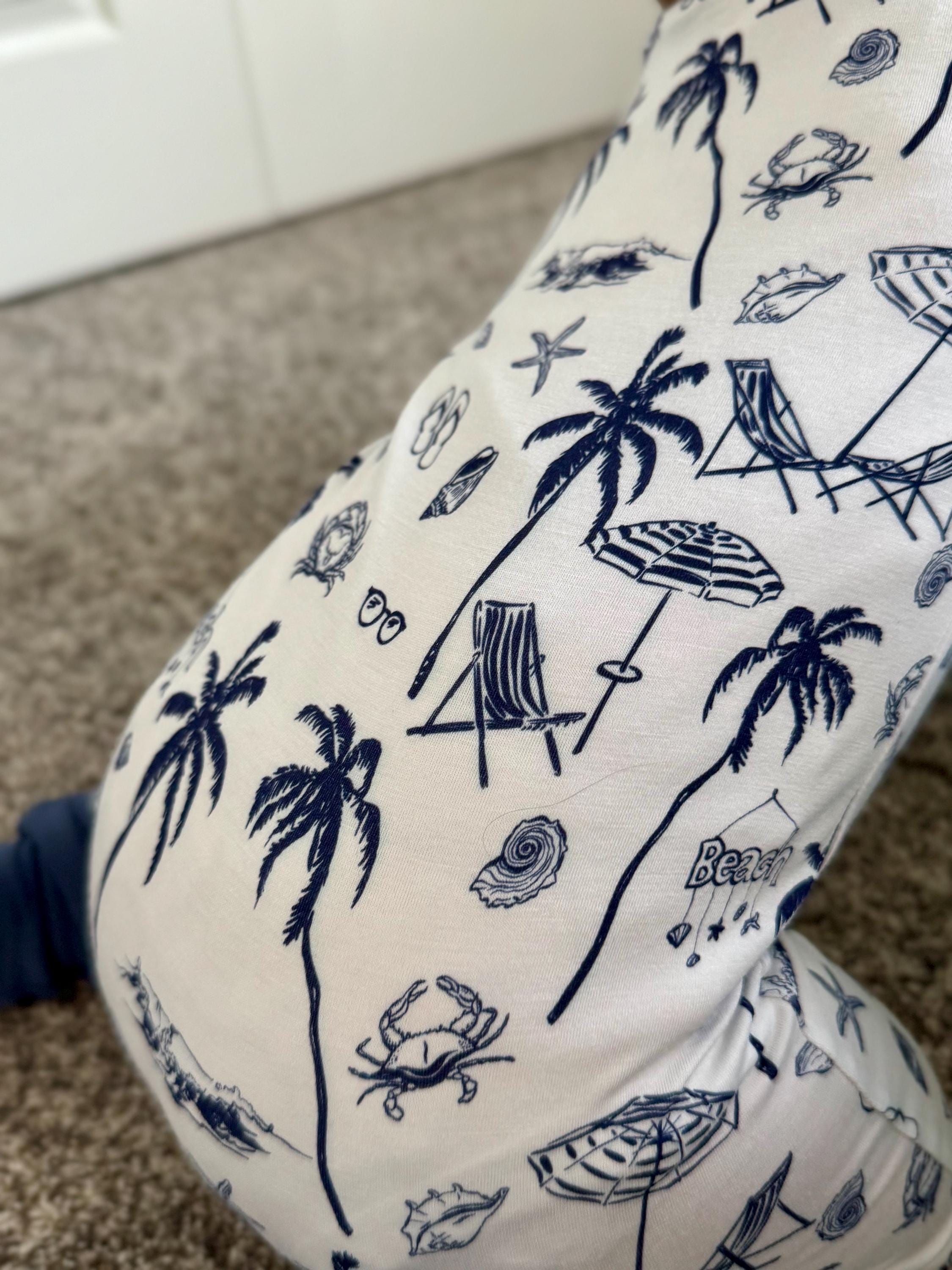 White bamboo baby pajama with blue beach-themed pattern on a carpeted floor.